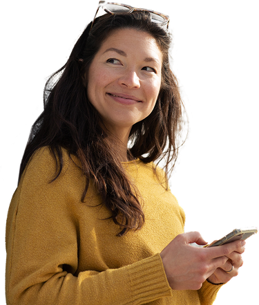 A confident, smiling young woman looking off to the side with her phone in both hands.